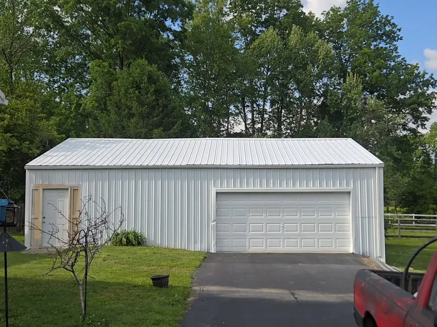 Metal garage before painting, faded white siding