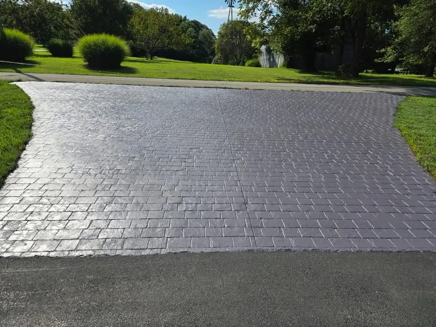 Stamped concrete driveway apron stained dark gray and sealed to a shine