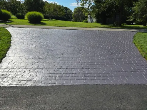 Stamped concrete driveway apron stained dark gray and sealed to a shine